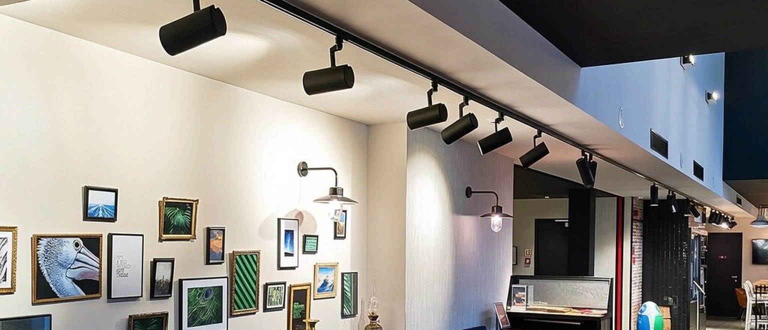48V magnetic track lighting — cylinder spots on a slim black track in a café interior